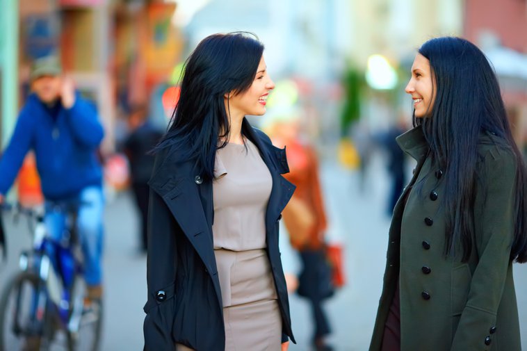 two professional latinas chatting on the street