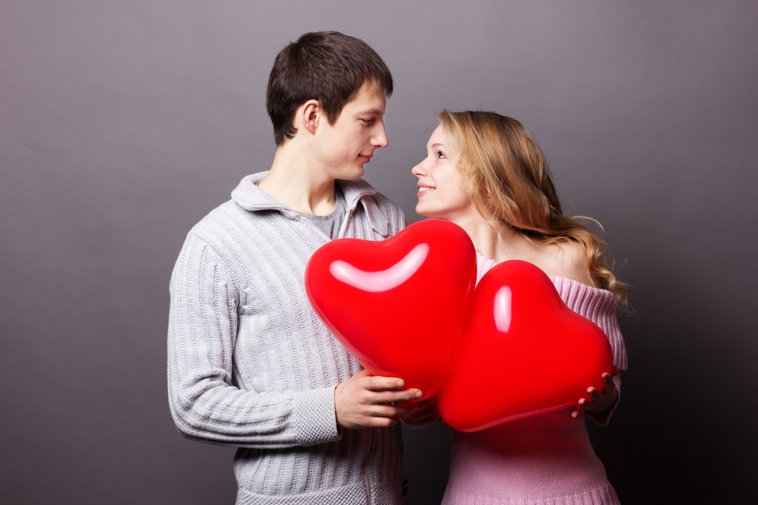 young couple holding heart balloons